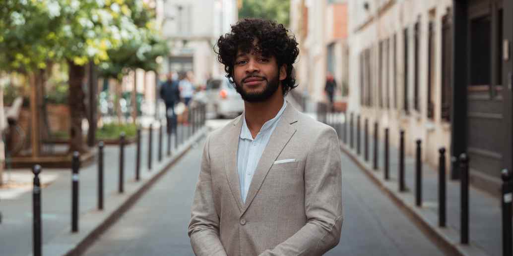 Homme en costume beige et chemise blanche à Paris souriant à la caméra