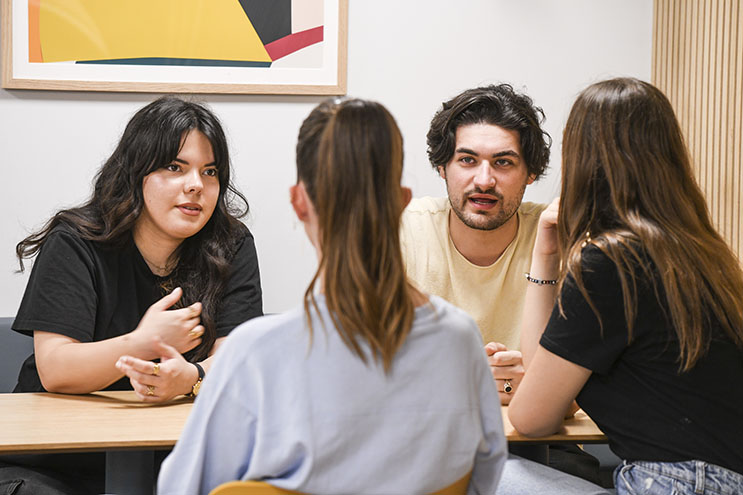Quatre étudiants discutent ensemble autour d'une table